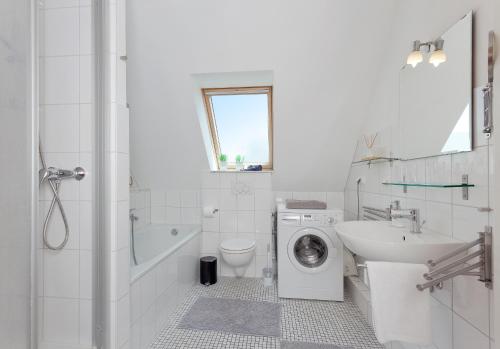 La salle de bains blanche est pourvue d'un lave-linge et d'un lavabo. dans l'établissement MEERerholung, à Zinnowitz