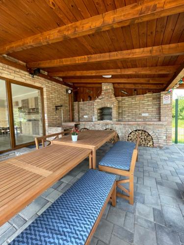 a patio with wooden tables and benches and a fireplace at Benige vendégház in Demjén