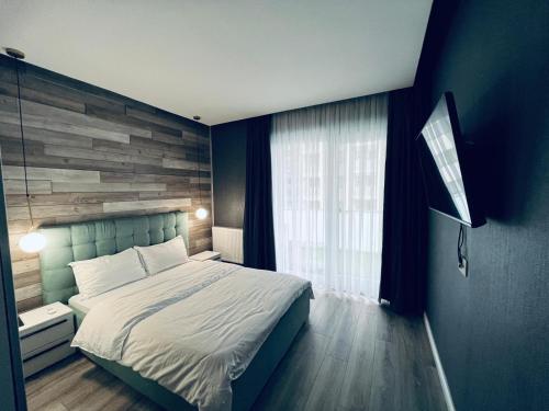 sypialnia z dużym łóżkiem i drewnianą ścianą w obiekcie The Garden Apartment w mieście Oradea