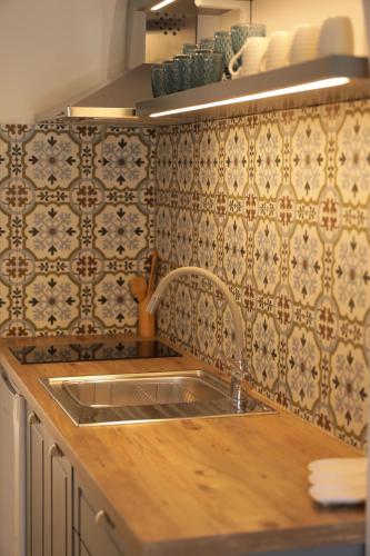 cocina con fregadero y pared de azulejos en Maria Apartments, en Hersonissos
