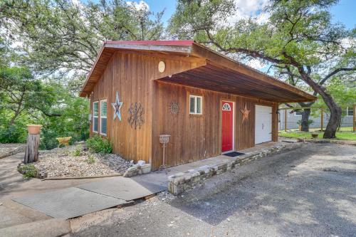 a small wooden building with a red door at Waterfront Spicewood Home Deck, Fire Pit and Grill in Spicewood