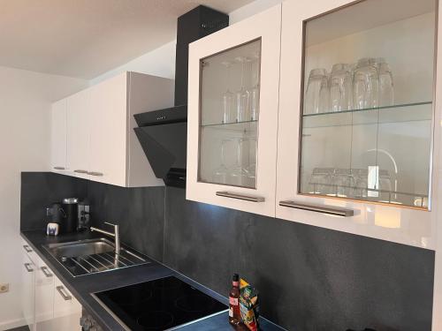 a kitchen with white cabinets and a sink and glasses at Apartment für 6 Crailsheim Zentrum Netflix 300 Mbit Wlan in Crailsheim