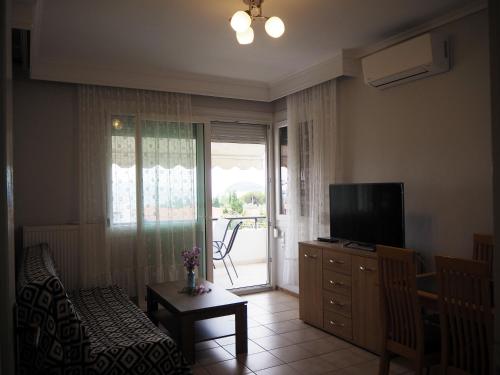 un soggiorno con divano, TV e porta scorrevole in vetro di Dimitris apartment a PalaiónTsiflíkion