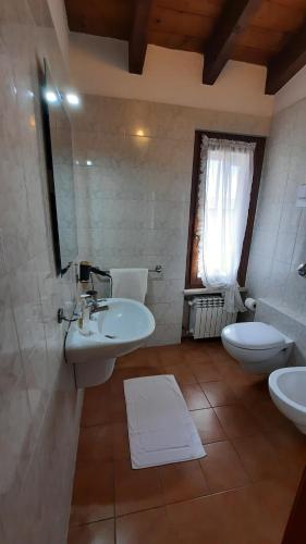 a bathroom with two sinks and a toilet and a mirror at Elisa Holidays in Puegnano del Garda