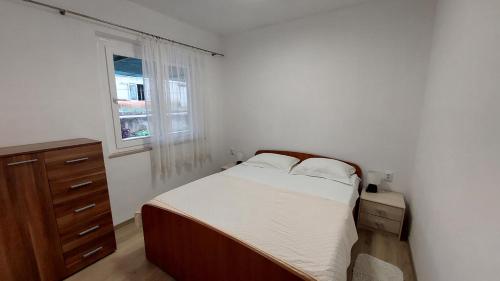 a bedroom with a bed and a dresser and a window at Apartman AnTe in Korčula