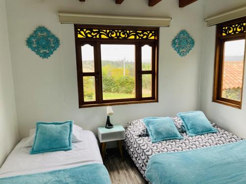 2 camas en una habitación con 2 ventanas en Casa turquesa, en Villa de Leyva