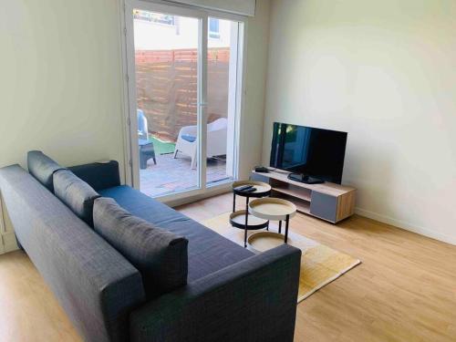 a living room with a couch and a television at Bel appartement terrasse+jardin in La Courneuve