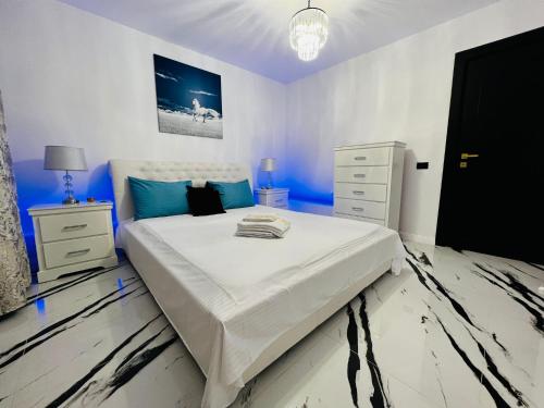 a bedroom with a large white bed with blue accents at Apartament Plaja Neversea in Constanţa