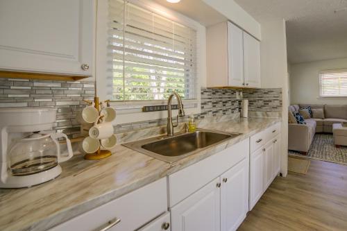a kitchen with white cabinets and a stainless steel sink at Easy Breezy Lake City Getaway - Walk to Beach! in Lake City
