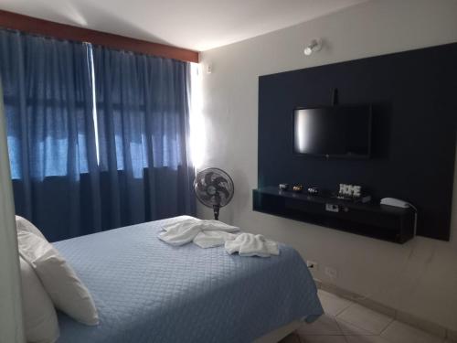 a bedroom with a bed and a flat screen tv at Apartamento 1010 in Goiânia