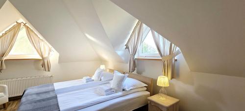 a bedroom with a bed with white sheets and two windows at Na Skarpie in Sasino