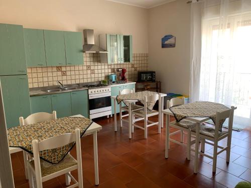 una cocina con armarios verdes, mesas y sillas en Cas'Ilenia Lido Azzurro, en Porto Empedocle