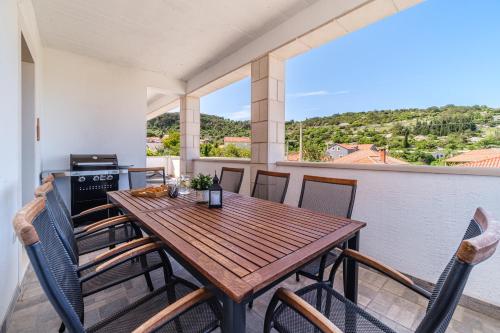 a wooden table and chairs on a balcony with a view at Guest house Barbara in Nerežišća