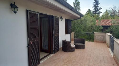a patio with two chairs and an open door at Domus Claudio in Villam in Pomezia