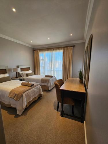 a hotel room with two beds and a desk at A Shot Of Luck in Mossel Bay