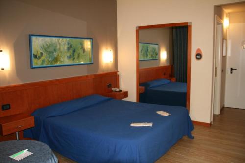Habitación de hotel con cama azul y espejo en Hotel Motel Fiore, en Fiorenzuola dʼArda