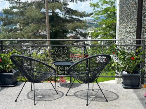 two chairs and a table on a balcony with flowers at Residence 33 in Sarajevo