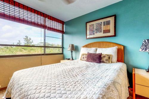 - une chambre avec un grand lit et un mur bleu dans l'établissement Maunaloa Shores 403, à Hilo