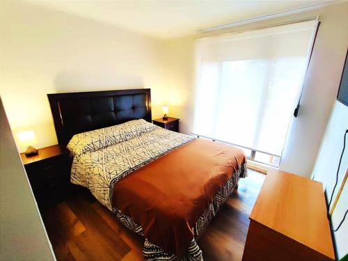 a bedroom with a bed and a large window at Depto 2D-1B con acceso directo a playa Cau Cau in Puchuncaví