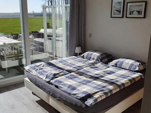 een slaapkamer met een bed en een raam bij Cosy holiday home on Lake Veere with the beach right at your doorstep in Kamperland