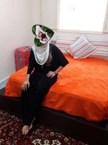 Eine Frau sitzt auf einem Bett mit Hut in der Unterkunft appartement kalaat mgouna in Irmina