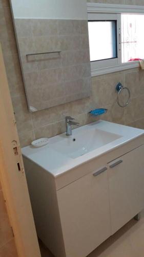 ein Badezimmer mit einem weißen Waschbecken und einem Spiegel in der Unterkunft appartement kalaat mgouna in Irmina