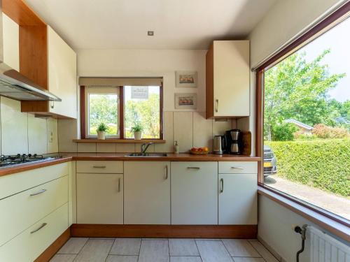 a kitchen with white cabinets and a large window at Holiday Home Zeeland near Westerschelde in Baarland