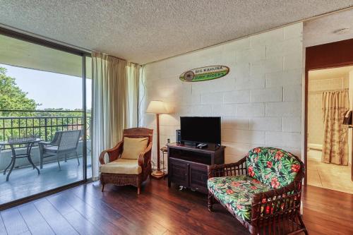 a living room with a tv and a couch and a chair at Maunaloa Shores 612 in Hilo