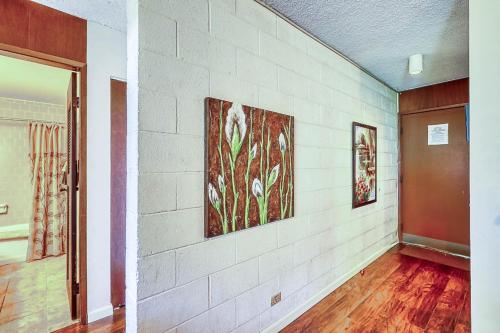 a room with a white brick wall with paintings on it at Maunaloa Shores 612 in Hilo