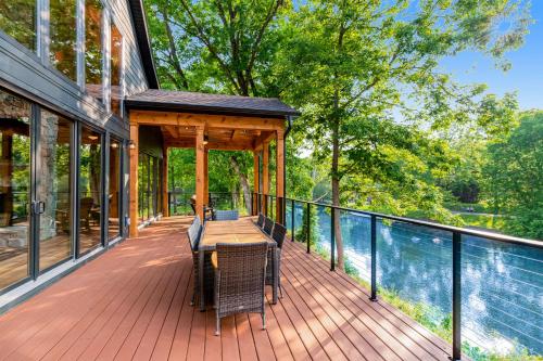 a covered deck with a table and chairs on a house at Enchanting Riverscape in Townsend