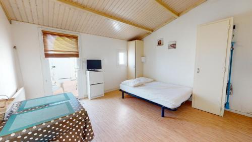 Cette petite chambre comprend un lit et une télévision. dans l'établissement Le Cocon en Bord de Mer, à Bretignolles-sur-Mer