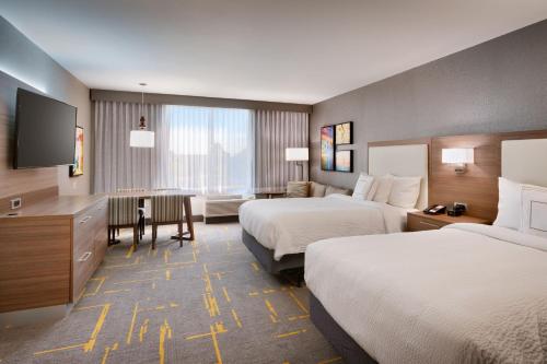 a hotel room with two beds and a desk with a table at TownePlace Suites by Marriott Los Angeles LAX/Hawthorne in Hawthorne