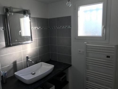 une salle de bain avec un lavabo, un miroir et une fenêtre dans l'établissement Maison plain pied 130m2, à Conca
