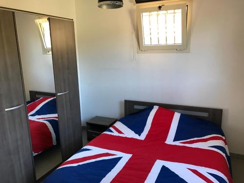 une chambre avec un lit rouge blanc et bleu et un miroir dans l'établissement Maison plain pied 130m2, à Conca