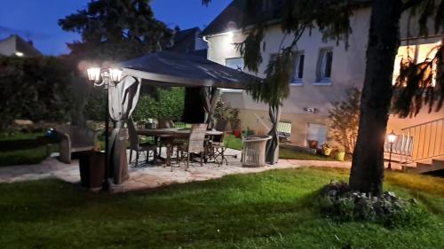 a backyard at night with a table and an umbrella at Grain de blé Location in Toury