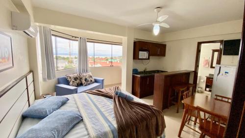 a bedroom with a bed and a kitchen with a window at Apart-Hotel Pacífico in Tramandaí