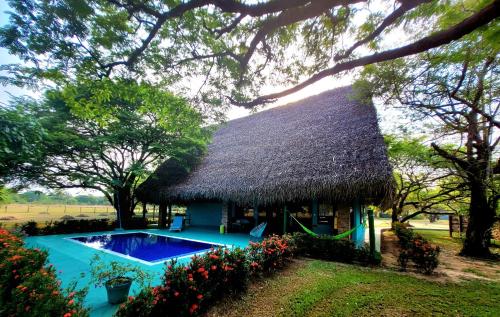 a house with a thatched roof and a swimming pool at Hato San Pablo in Guayabal