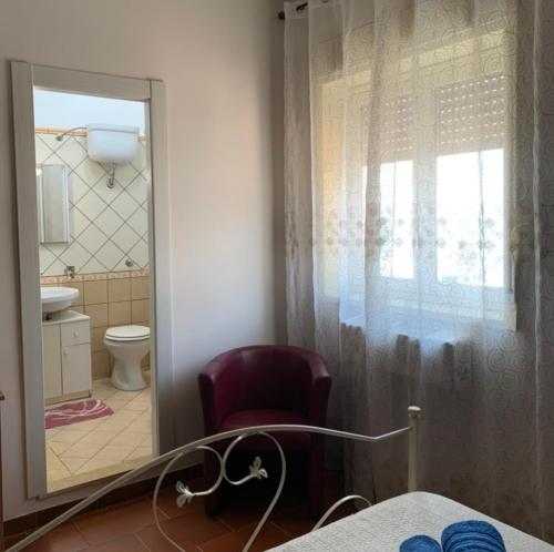 baño con espejo, silla y aseo en Cas'Ilenia Lido Azzurro en Porto Empedocle