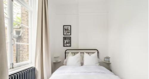 Spacious 1 bed in Primrose Hill في لندن: غرفة نوم بيضاء بها سرير ونافذة