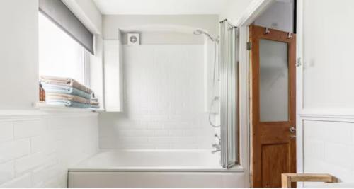 baño blanco con ducha y lavamanos en Spacious 1 bed in Primrose Hill, en Londres
