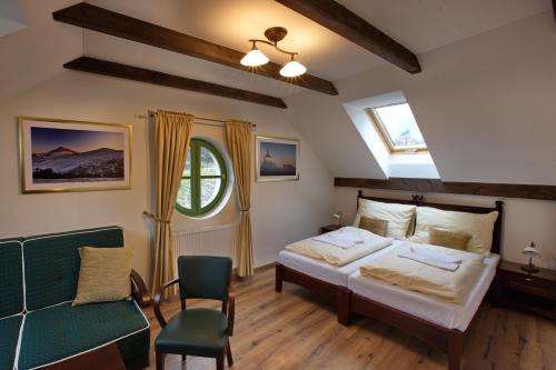 a bedroom with two beds and a green chair at Vila Magnolia in Banská Štiavnica