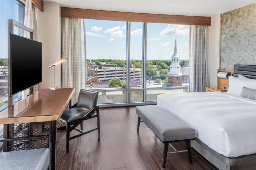 a hotel room with a bed and a desk and a large window at Lancaster Marriott at Penn Square in Lancaster