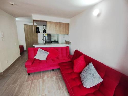 a red couch in a living room with red pillows at Espectacular Aparta Estudio Armenia Quindío in Armenia