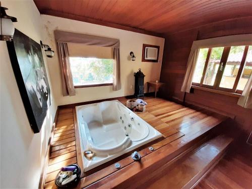 a large bath tub in a room with wooden floors at Recanto da Paz Tur - Relax e charme na serra in Miguel Pereira