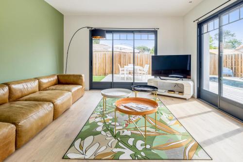 un salon avec un canapé et une télévision dans l'établissement Villa La Hume - Welkeys, à Gujan-Mestras