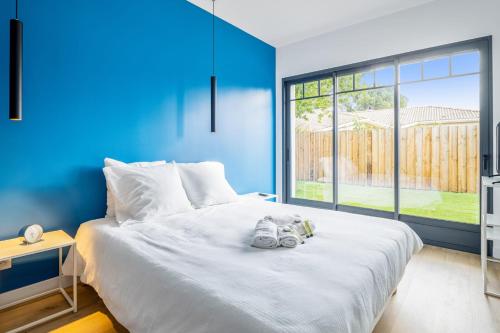 une chambre avec un lit blanc avec un mur bleu dans l'établissement Villa La Hume - Welkeys, à Gujan-Mestras