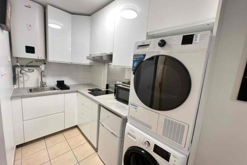 a white kitchen with a washer and dryer in it at Very quiet apartment with balcony in Saint-Denis