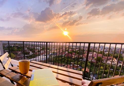 a book on a bench on a balcony with a sunset at Sol Apartment - self check-in, free parking in Oradea