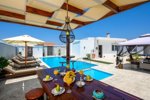 an outdoor dining area with a table and a pool at Pervolia House in Kremasti