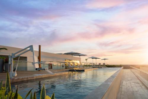 メリダにあるCourtyard by Marriott Merida Downtownのパラソル付きのリゾートのプール